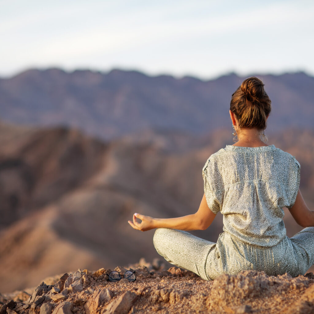 Woman practicing yoga in the mountains in the desert
